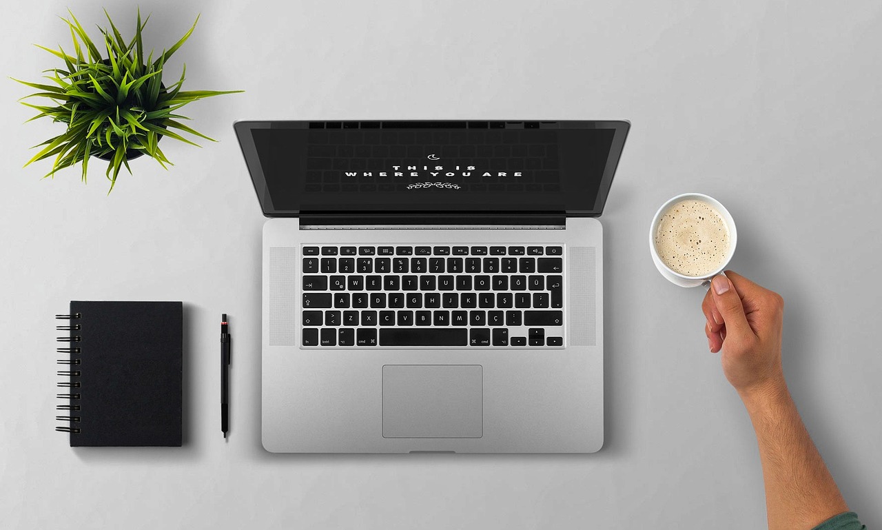 Minimalist workspace with laptop, notebook, and coffee cup representing a clutter-free digital life.