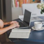Minimalist home office setup with laptop, notebook, and plant for calm and focused work.