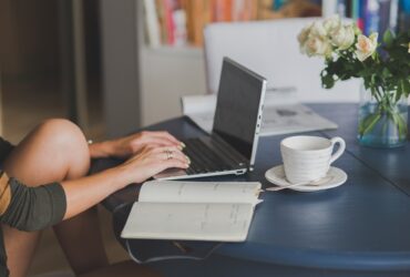 Minimalist home office setup with laptop, notebook, and plant for calm and focused work.